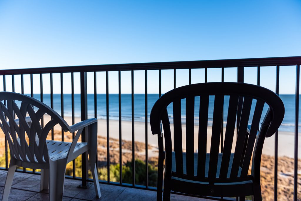 Seascape view through balcony railing with two chairs at Myrtle Beach resort hotel condo condominium apartment waterfront building, South Carolina